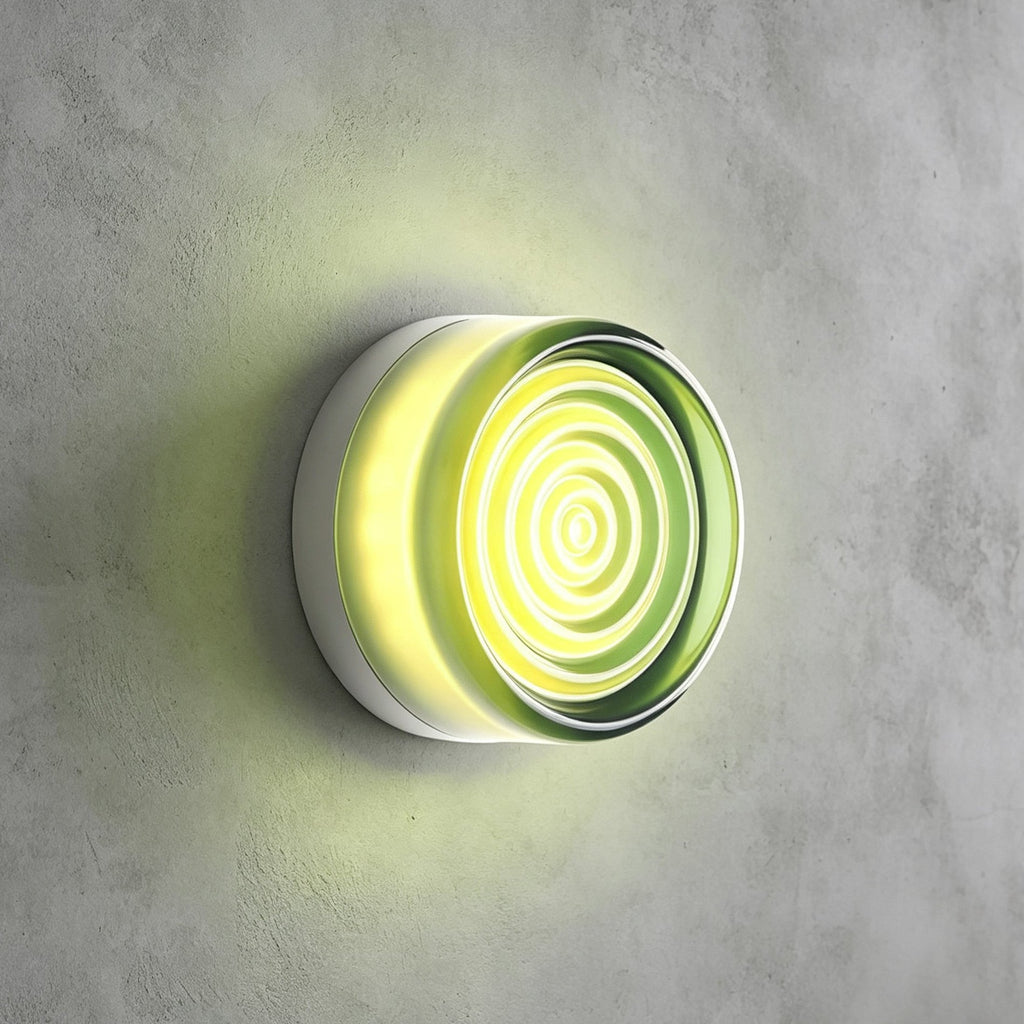 Pale green rippled-glass Clérachic wall light glowing lime against a grey concrete wall, a faint green halo around it.