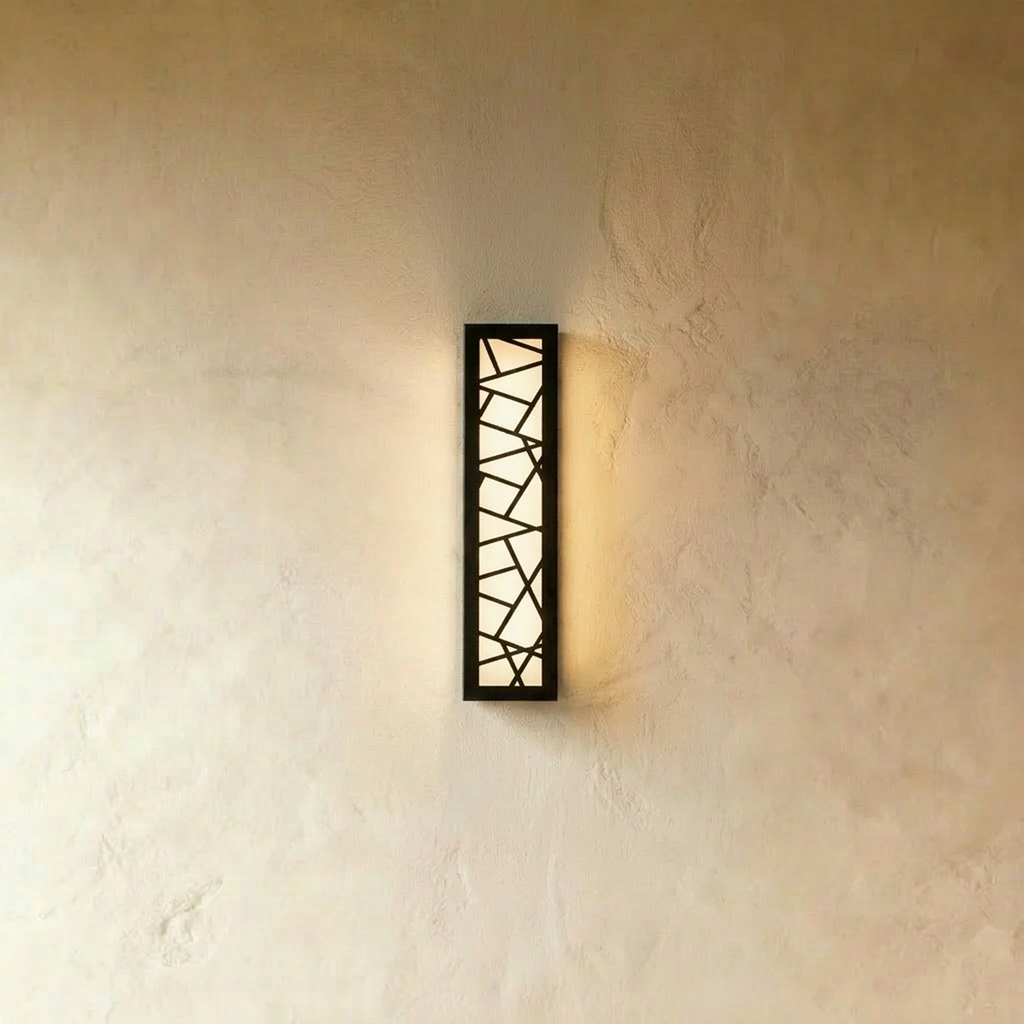 Clérachic slim black wall lamp with an angular cut-out pattern over a warm white diffuser, mounted on a textured plaster wall.
