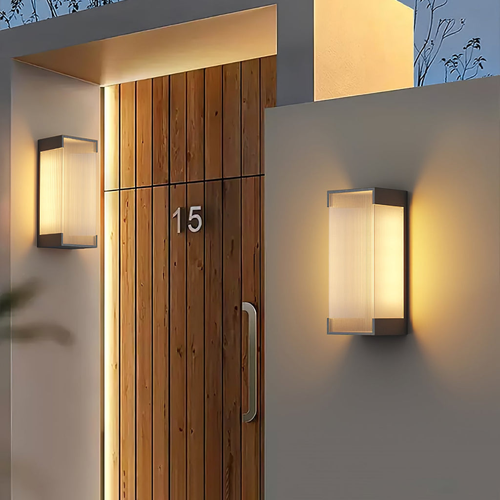 Clérachic wall lights on either side of a timber front door numbered 15, each glowing softly against the walls.