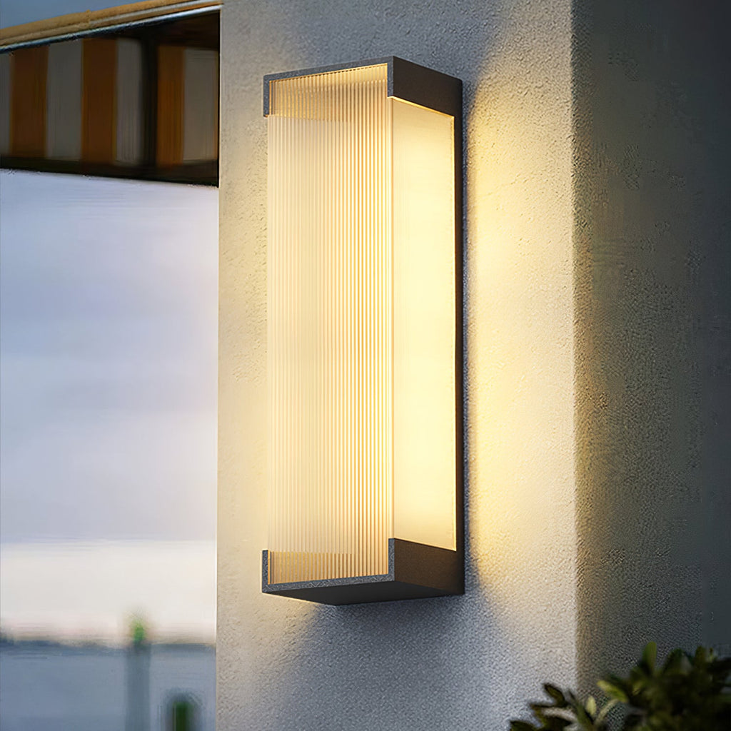 Close-up of the ribbed panel and black end caps of this Clérachic wall light, lit warm on a pale rendered wall.