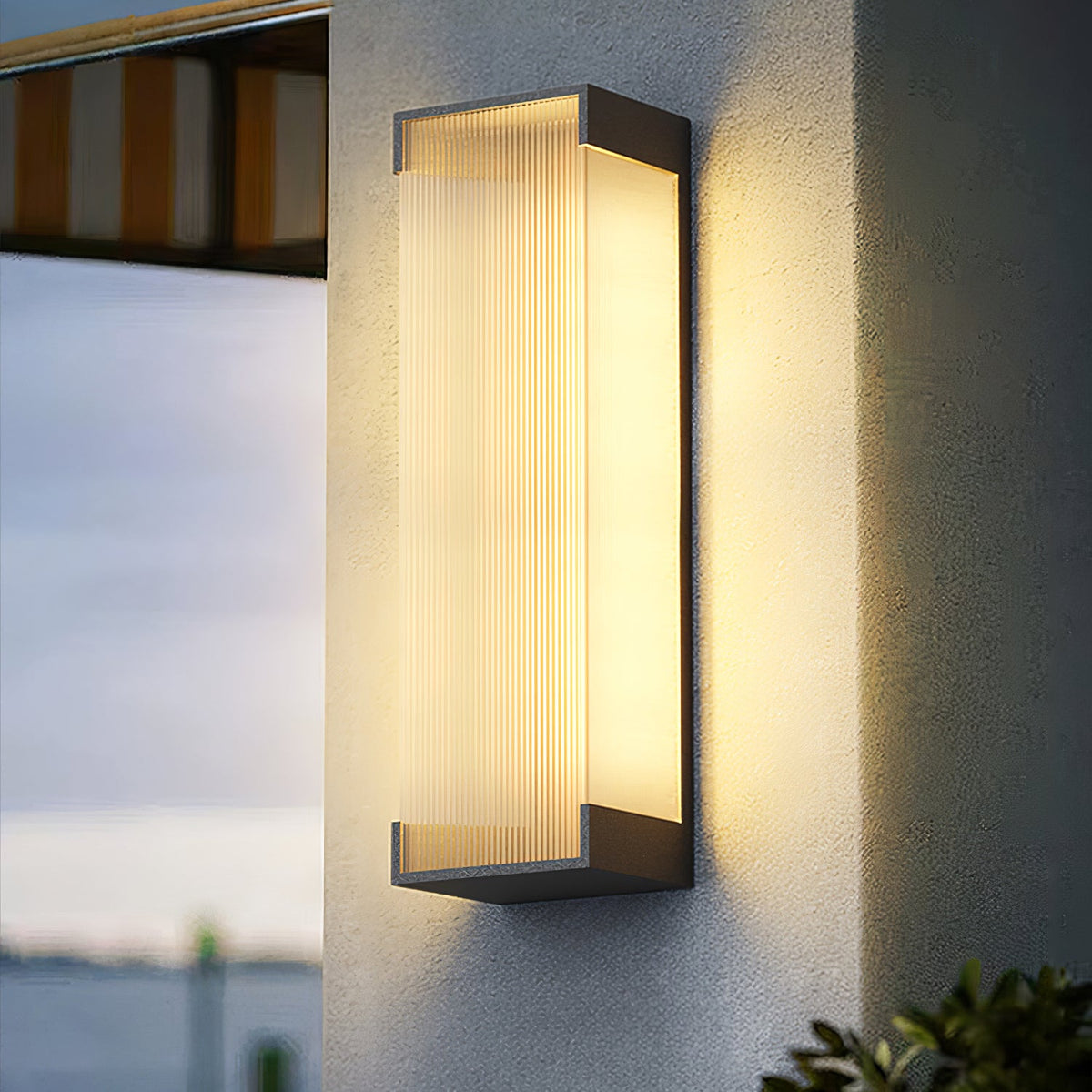 Close-up of the ribbed panel and black end caps of this Clérachic wall light, lit warm on a pale rendered wall.