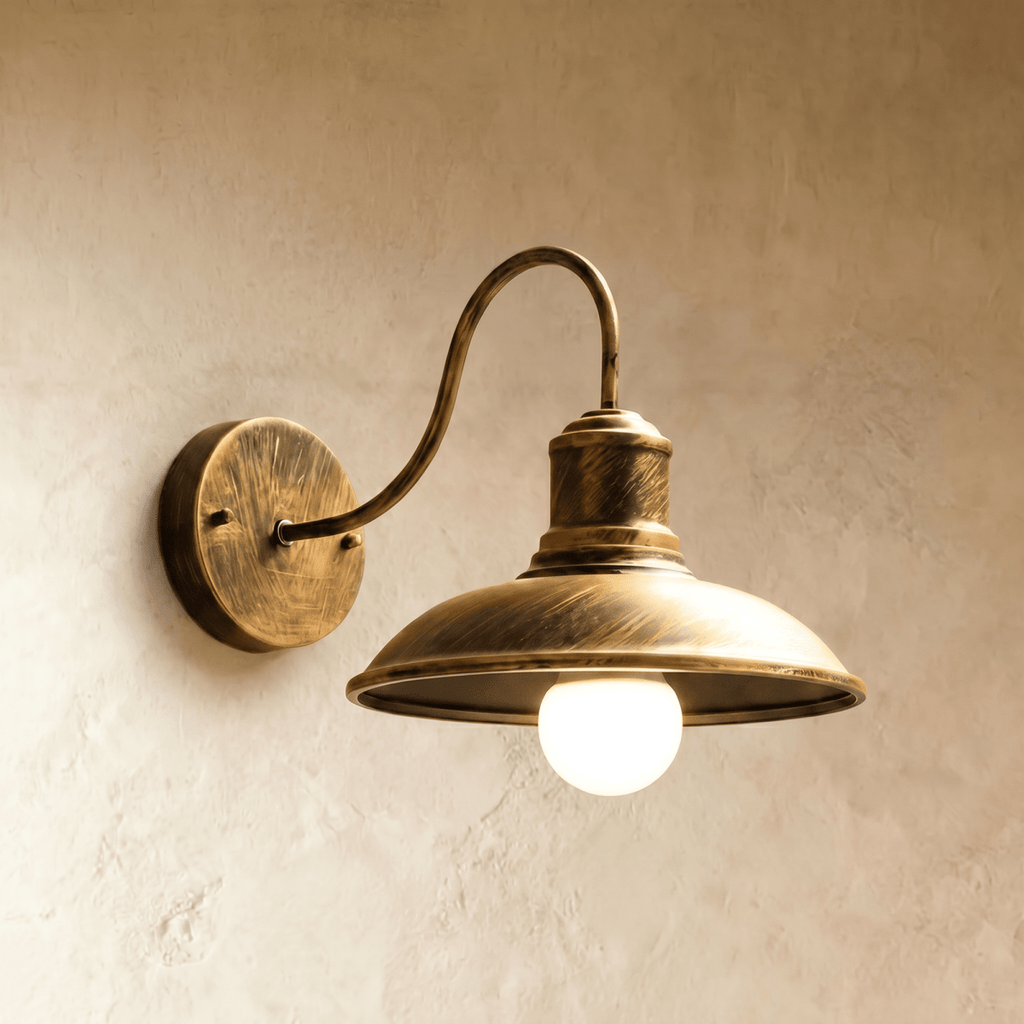 Clérachic bronze gooseneck wall lamp with a broad downward-facing dome shade and a lit opal globe bulb on plaster