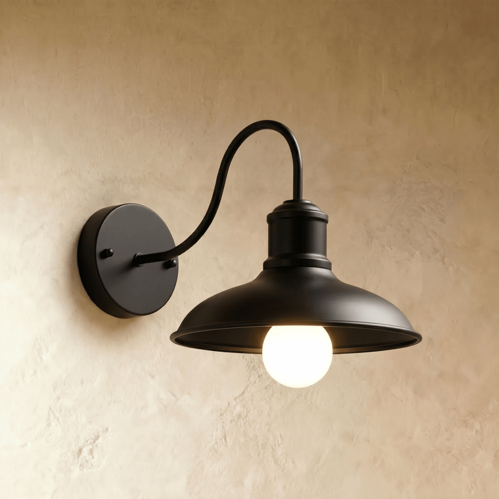 Clérachic matte black gooseneck wall lamp with a wide downward dome shade and a glowing opal bulb on plaster