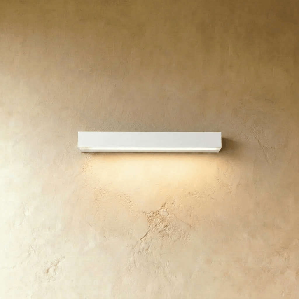 Clérachic slim white rectangular wall light casting a soft warm wash of light down a limewashed wall.