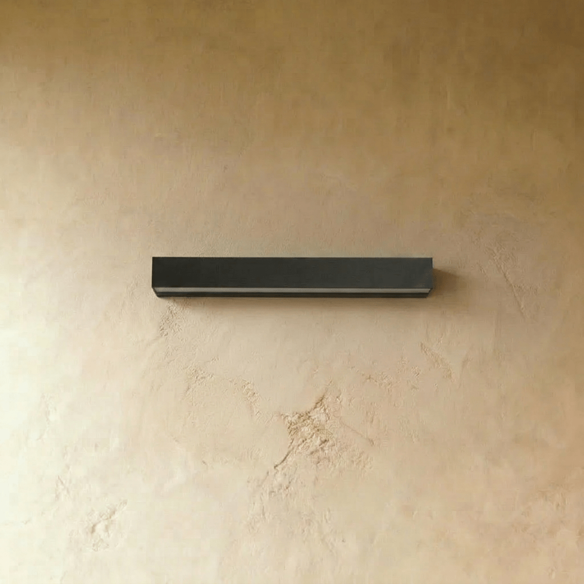 Clérachic slim black rectangular wall light, switched off, with its pale diffuser strip along the underside, on limewash.