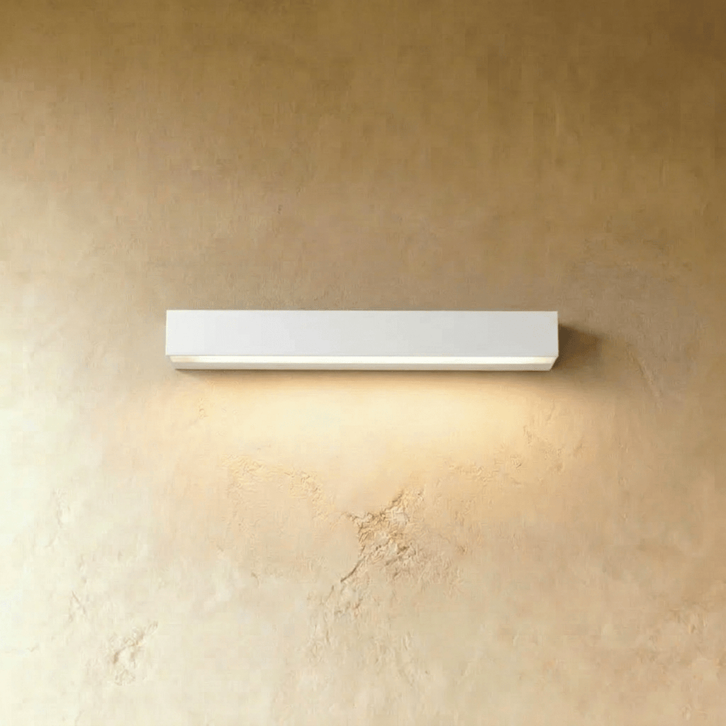 Clérachic longer slim white wall light with a lit diffuser strip, washing warm light down a limewashed wall.
