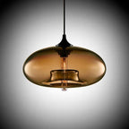 Studio view of the Clérachic oval blown glass pendant light in brown glass, the inner collar and filament bulb showing through.