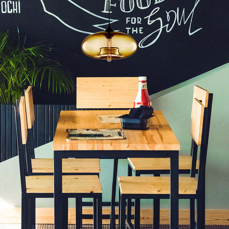 Clérachic oval blown glass pendant light in amber glass warming a pine table in a casual café corner.