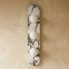 Clérachic three-globe wall light on a long rounded marble backplate with dark veining, unlit against a plaster wall.