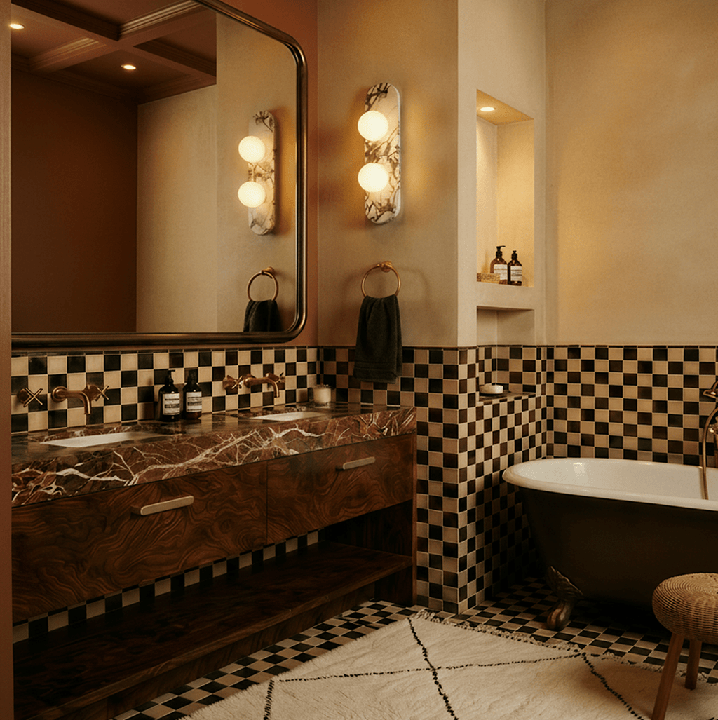 Clérachic pair of two-globe marble wall lights beside a large mirror, a marble-top basin unit and chequered tiles.