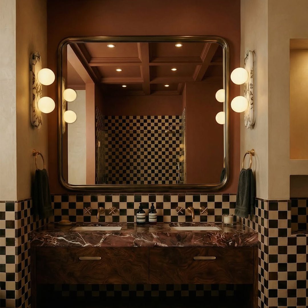 Clérachic two-globe marble wall lights flanking a rounded mirror above a walnut basin unit with chequered tile walls.