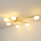 Clérachic Oval Opal Glass Ceiling Light in brass, six lit shades washing warm light across the ceiling of a dim room.