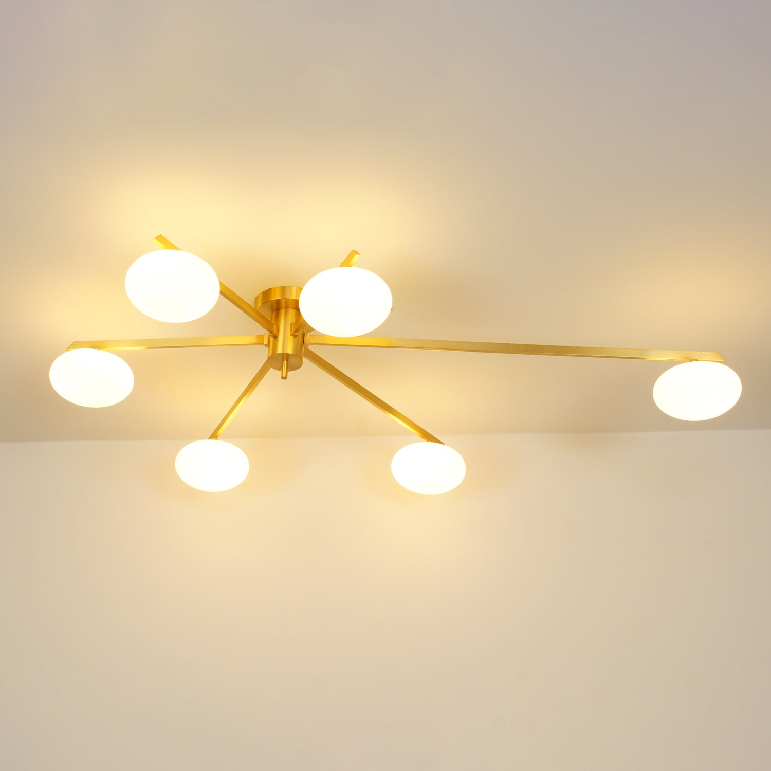 Clérachic Oval Opal Glass Ceiling Light switched on in brass, six shades lighting a room from the ceiling line.