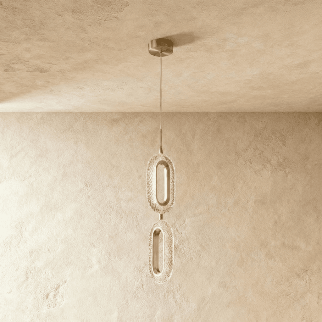 Clérachic two-head pendant of stacked oval rings in brushed brass and textured clear acrylic, hung from a round brass canopy.