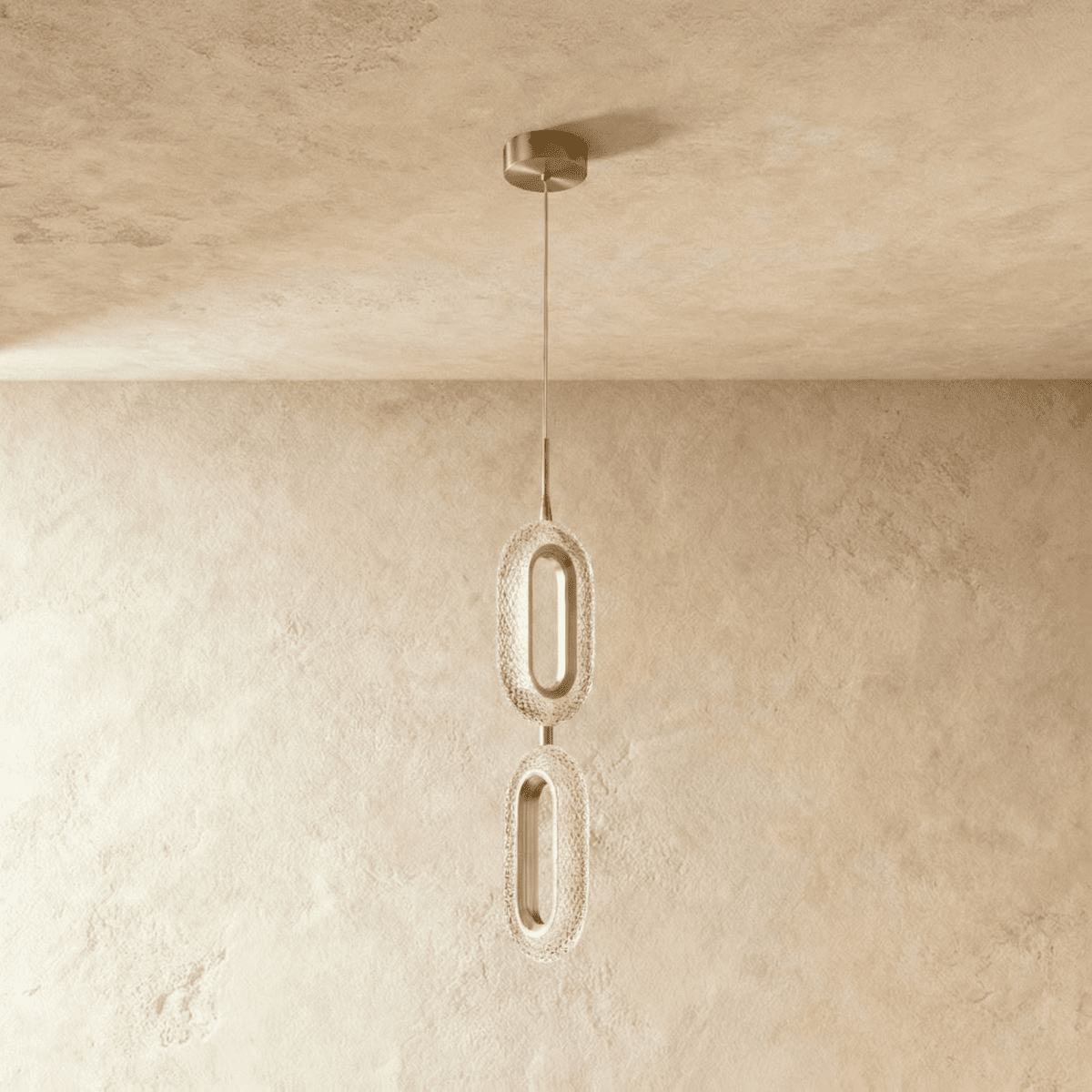 Clérachic two-head pendant of stacked oval rings in brushed brass and textured clear acrylic, hung from a round brass canopy.