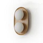 Studio view of this Clérachic wall light in a light wood finish, two frosted globes on a soft-edged oval frame.