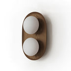 Studio view of this Clérachic wall light in a dark walnut finish, with two frosted globes on an oval frame with visible grain.