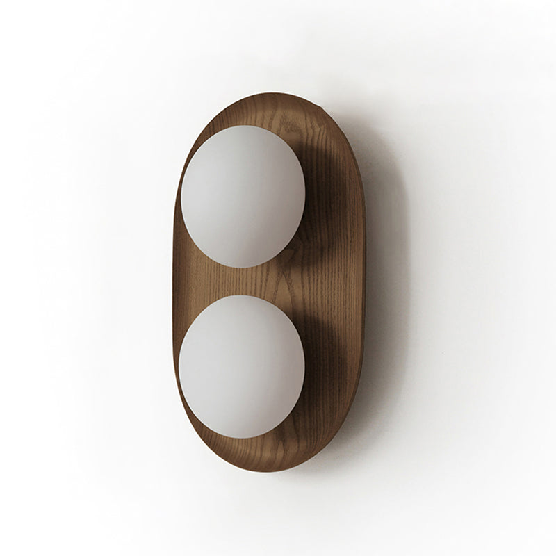Studio view of this Clérachic wall light in a dark walnut finish, with two frosted globes on an oval frame with visible grain.