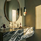 Clérachic teal pendant with a sage plate and terracotta disc beside a round mirror and a green marble washstand.