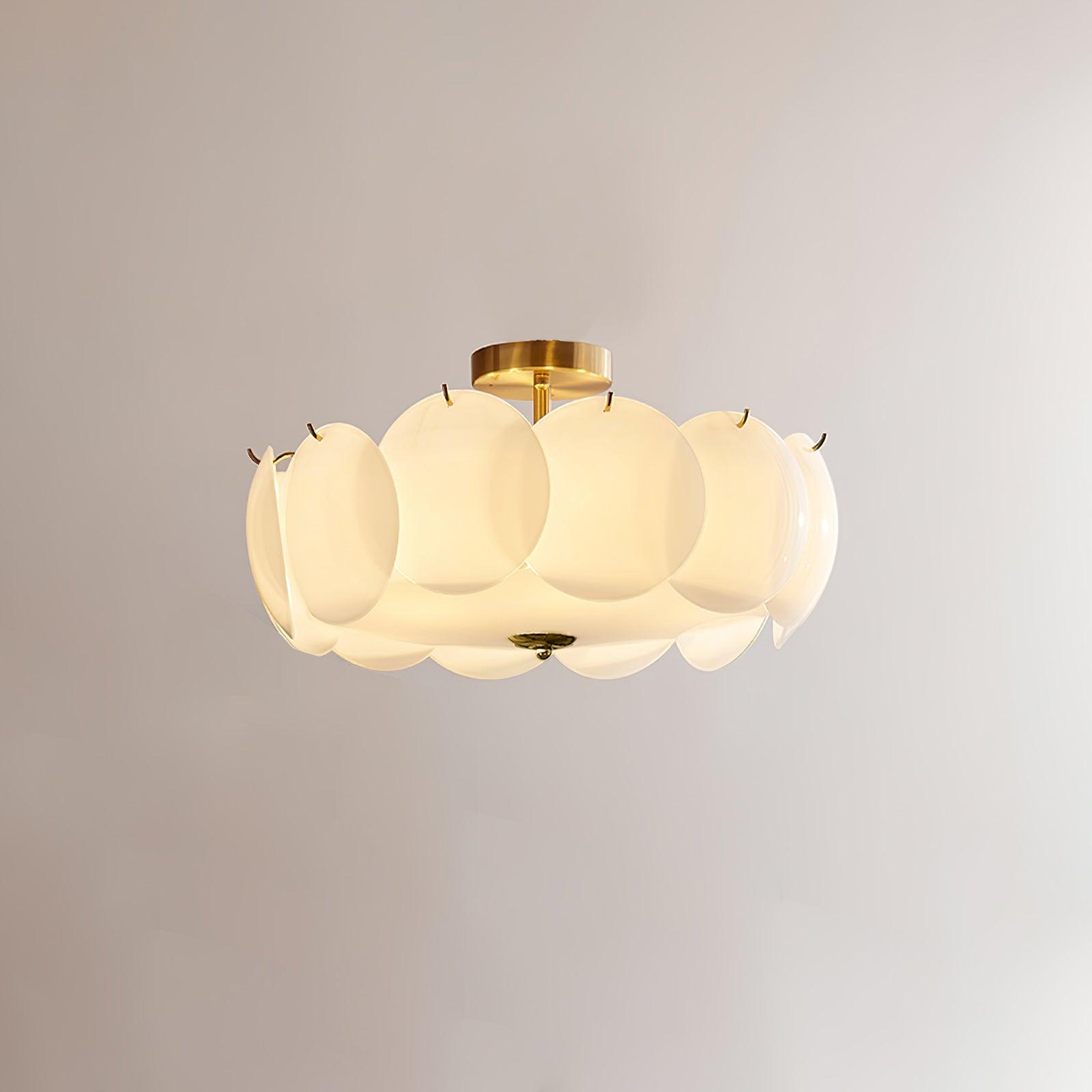 The Clérachic overlapping glass disc semi-flush ceiling light lit, its brass stem and glass discs glowing warmly.