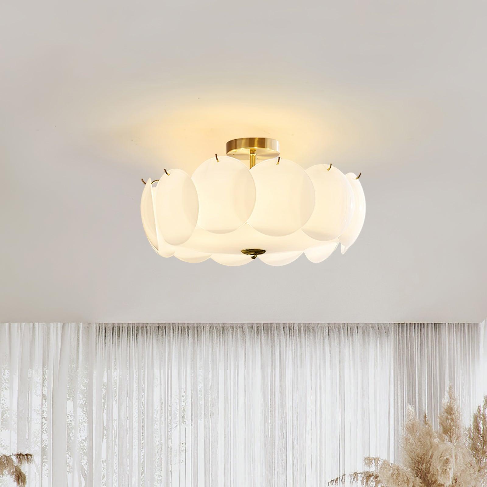 The Clérachic overlapping glass disc semi-flush ceiling light lit in a room with sheer curtains and dried pampas grass.