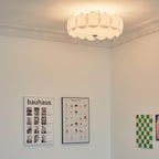 The Clérachic overlapping glass disc semi-flush ceiling light lit in a room with a Bauhaus poster and a chair-design print.