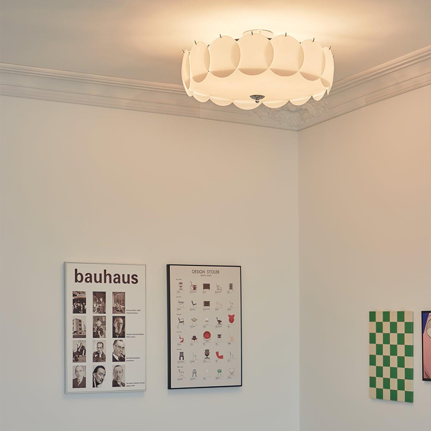The Clérachic overlapping glass disc semi-flush ceiling light lit in a room with a Bauhaus poster and a chair-design print.