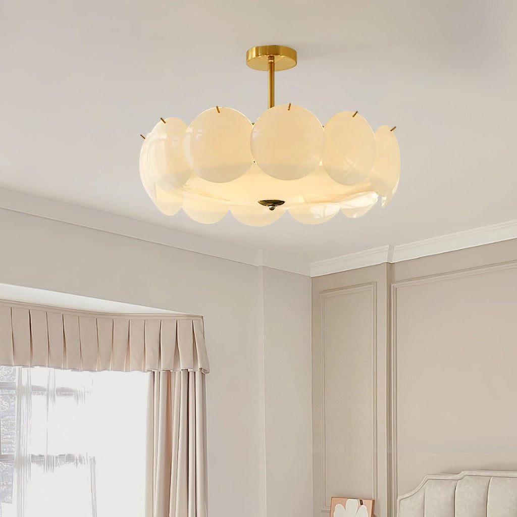 The Clérachic overlapping glass disc semi-flush ceiling light lit in a bedroom with a pleated curtain valance and tufted headboard.