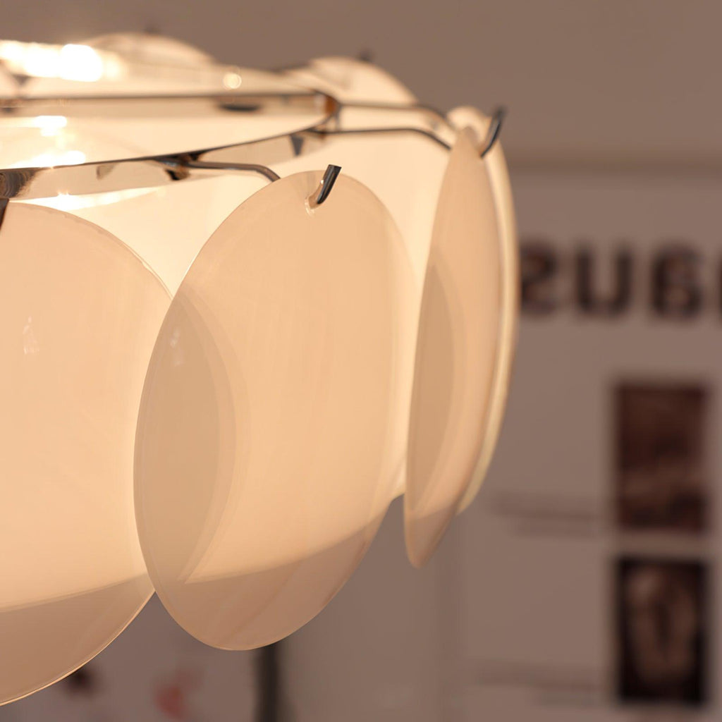 Extreme close-up of the Clérachic overlapping glass disc semi-flush ceiling light's hooked glass discs, glowing warm.