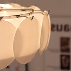 Extreme close-up of the Clérachic overlapping glass disc semi-flush ceiling light's hooked glass discs, glowing warm.