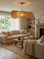 In a living room with linen sofas and a stone fireplace, this Clérachic pendant lights a wood coffee table.