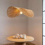 Close above a round stone table set with white dishes, this Clérachic pendant glows against an exposed brick wall.