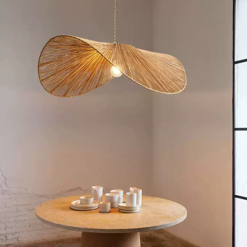 Close above a round stone table set with white dishes, this Clérachic pendant glows against an exposed brick wall.