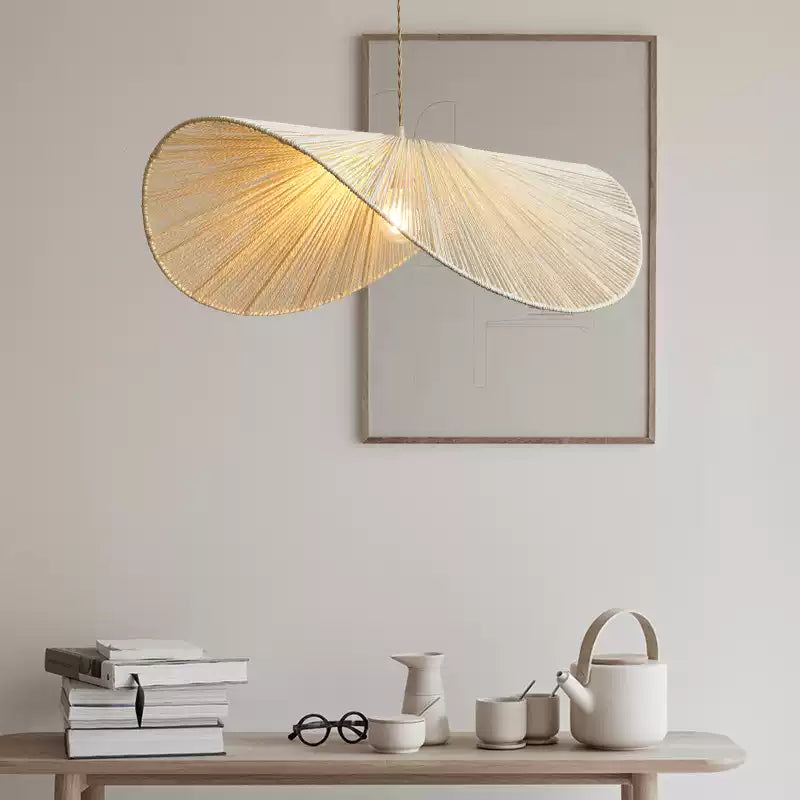 In a lighter beige finish, this Clérachic pendant hangs lit beside a console table styled with books and a vase.