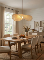 Above a wood dining table with upholstered chairs, this Clérachic pendant glows beside a shiplap wall.