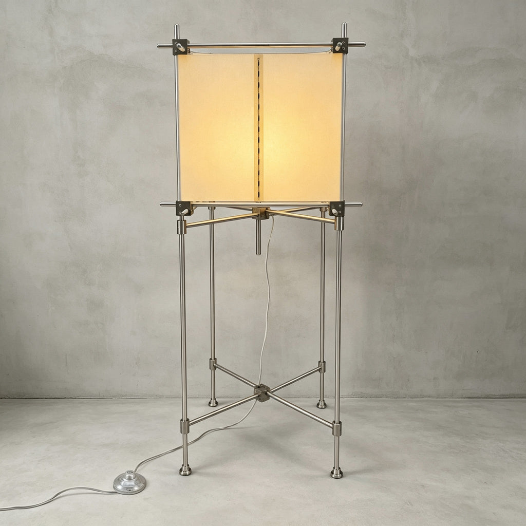 Full view of the taller Clérachic floor lamp, a parchment cube shade on a slim metal frame with a foot switch, on a grey backdrop.