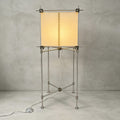 Full view of the taller Clérachic floor lamp, a parchment cube shade on a slim metal frame with a foot switch, on a grey backdrop.