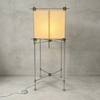 Full view of the taller Clérachic floor lamp, a parchment cube shade on a slim metal frame with a foot switch, on a grey backdrop.