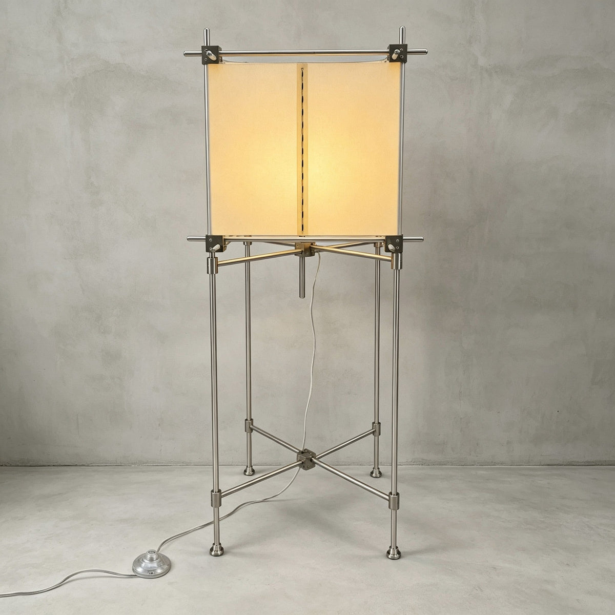 Full view of the taller Clérachic floor lamp, a parchment cube shade on a slim metal frame with a foot switch, on a grey backdrop.