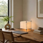 Beside a laptop and a stack of books on a wooden desk by the window, this Clérachic cube lamp glows in a corner.