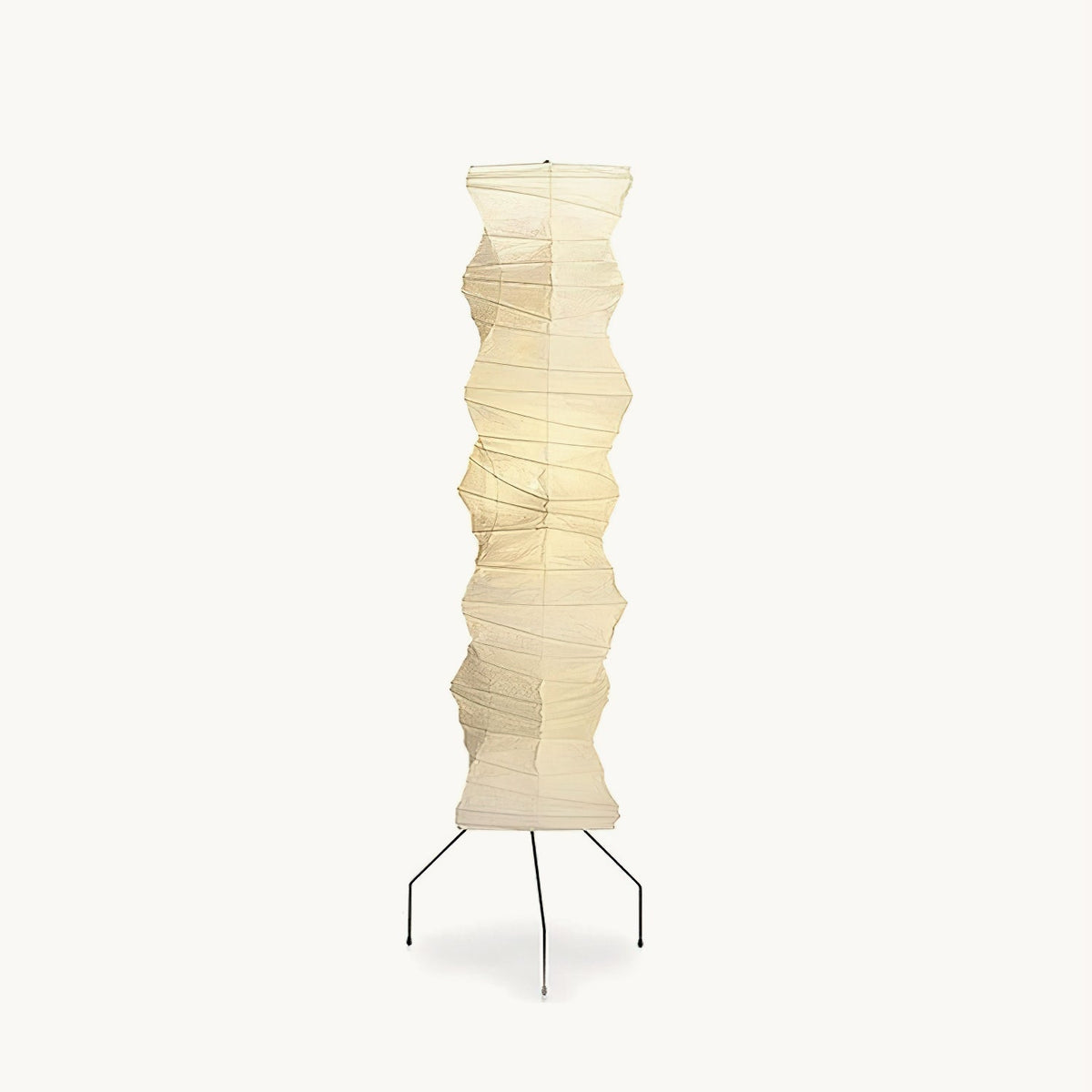 Tall folded washi paper floor lamp from Clérachic on a white backdrop, with a pale shade on three thin black iron legs.