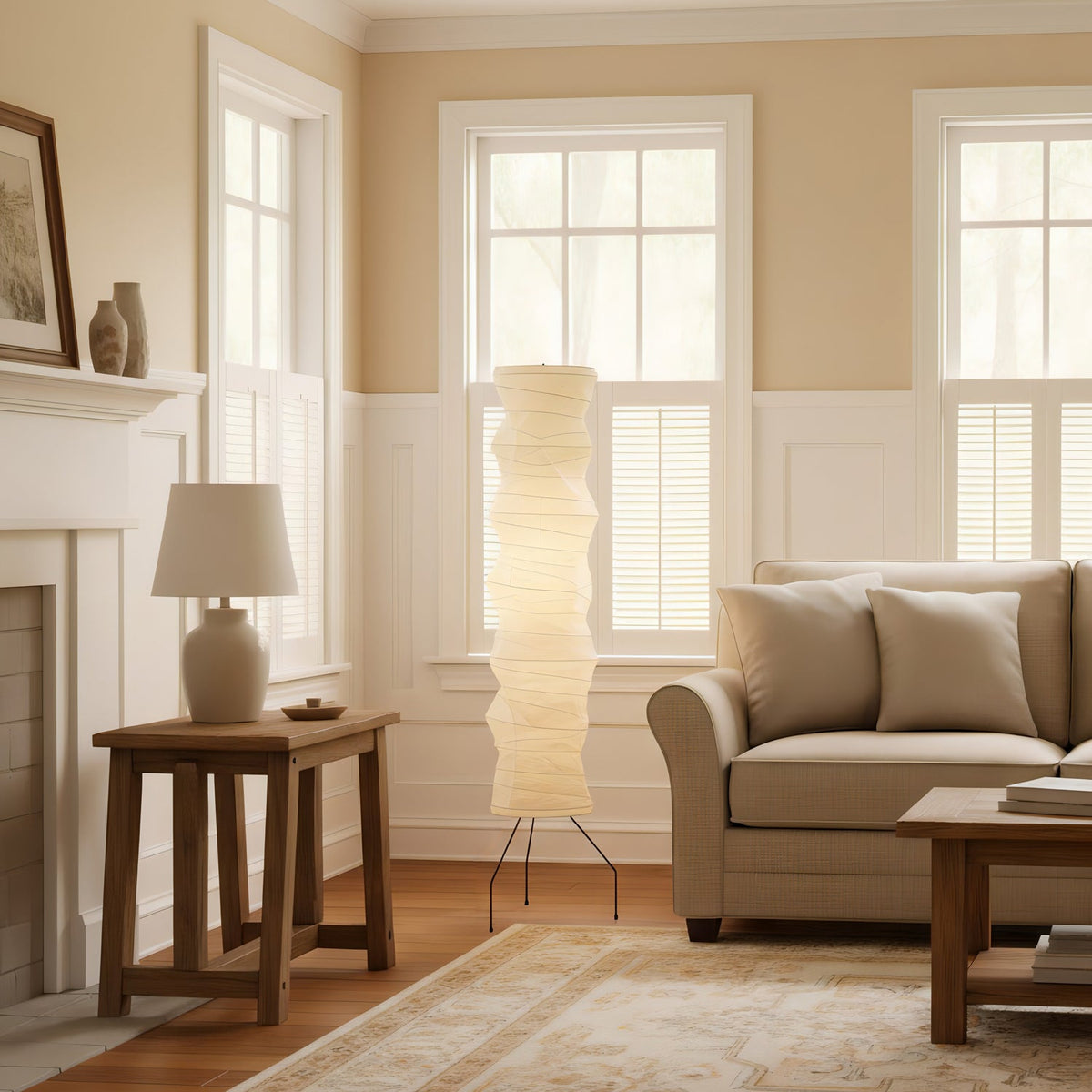 Clérachic tall paper floor lamp lit in a panelled living room with a wooden side table, a table lamp and a beige sofa.