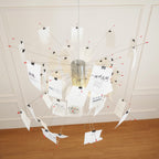 Seen from below, the metal core and red-tipped wire arms of this Clérachic pendant carry cards printed with calligraphic text.
