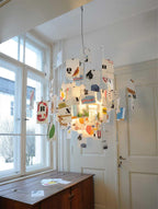 This Clérachic paper pendant is lit up by tall windows, its printed alphabet cards glowing warm against a white door.