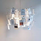 Cards printed with short quotes in black and blue hang from the arms of this Clérachic pendant against a plain pale wall.
