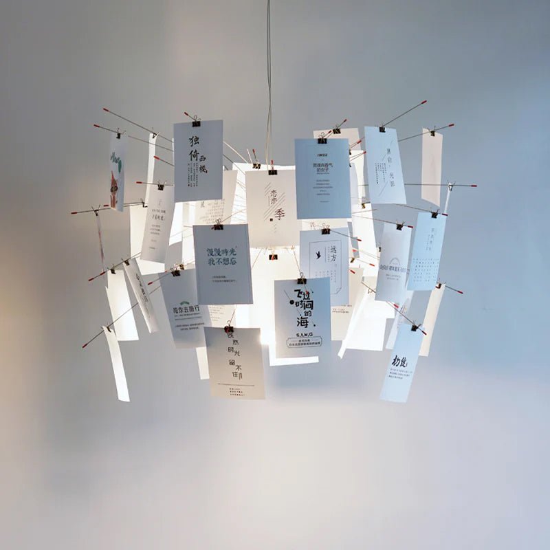 Front view of a Clérachic paper pendant with blue-tinted cards in calligraphic script clipped to red-tipped wire arms.