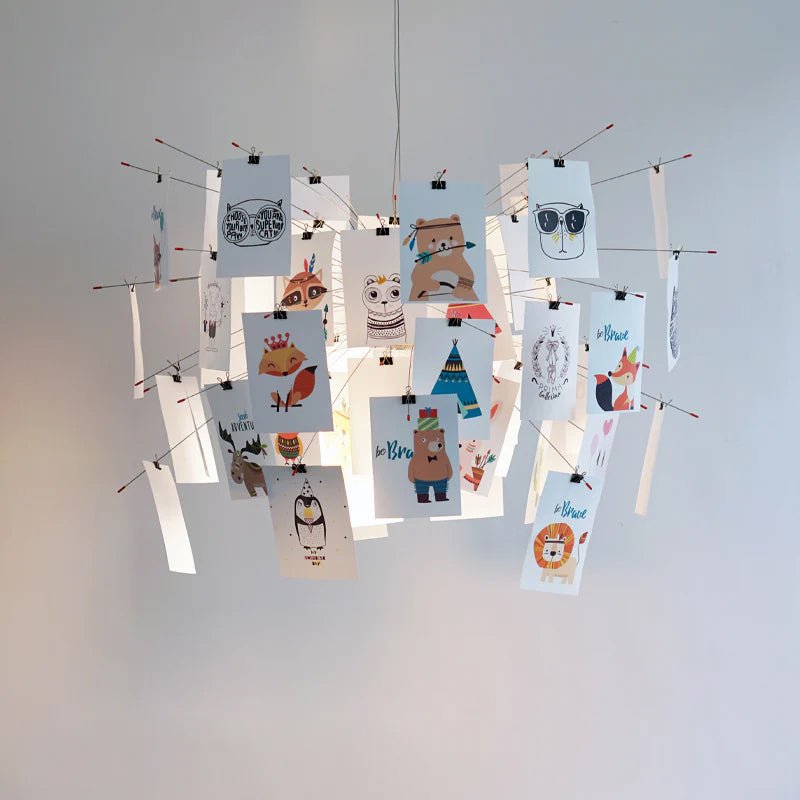 A Clérachic pendant hung with cards of cartoon animals, from bears to owls, on red-tipped wire arms, in front of a pale wall.
