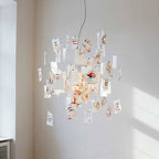 Cards with painted faces and red lips cover this Clérachic paper pendant, lit from within in a white corner with soft sunlight.
