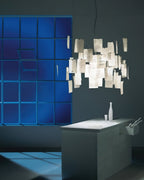 Against a dark wall and blue glass blocks, a Clérachic paper pendant glows above a stone-topped kitchen island.