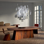 Pale handwritten notes cluster on this Clérachic paper pendant, hung above a walnut table in a bright room with tall windows.